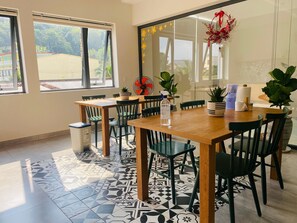 Un espace repas avec une table et des chaises en bois, un sol à motifs et une vue sur la verdure à l’extérieur.