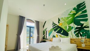 Un dormitorio con una cama grande, cabecera de madera y un mural con motivos de hojas tropicales.