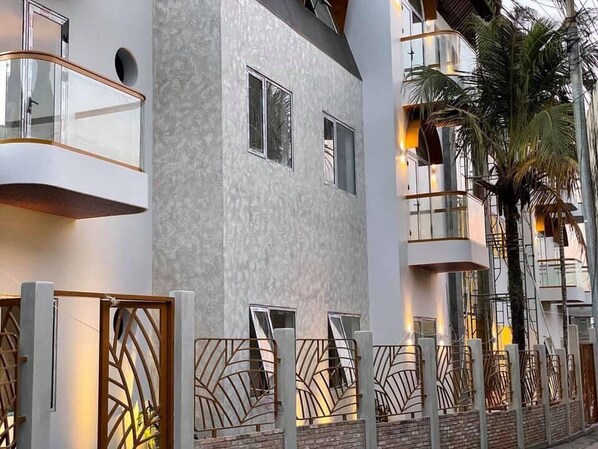 Un edificio moderno con balcones, fachada texturizada y puertas metálicas decorativas.
