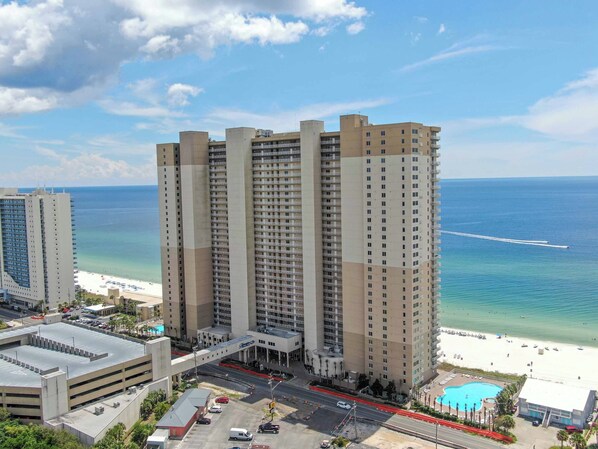 A high-rise hotel with multiple floors, a parking garage, and a beach view.