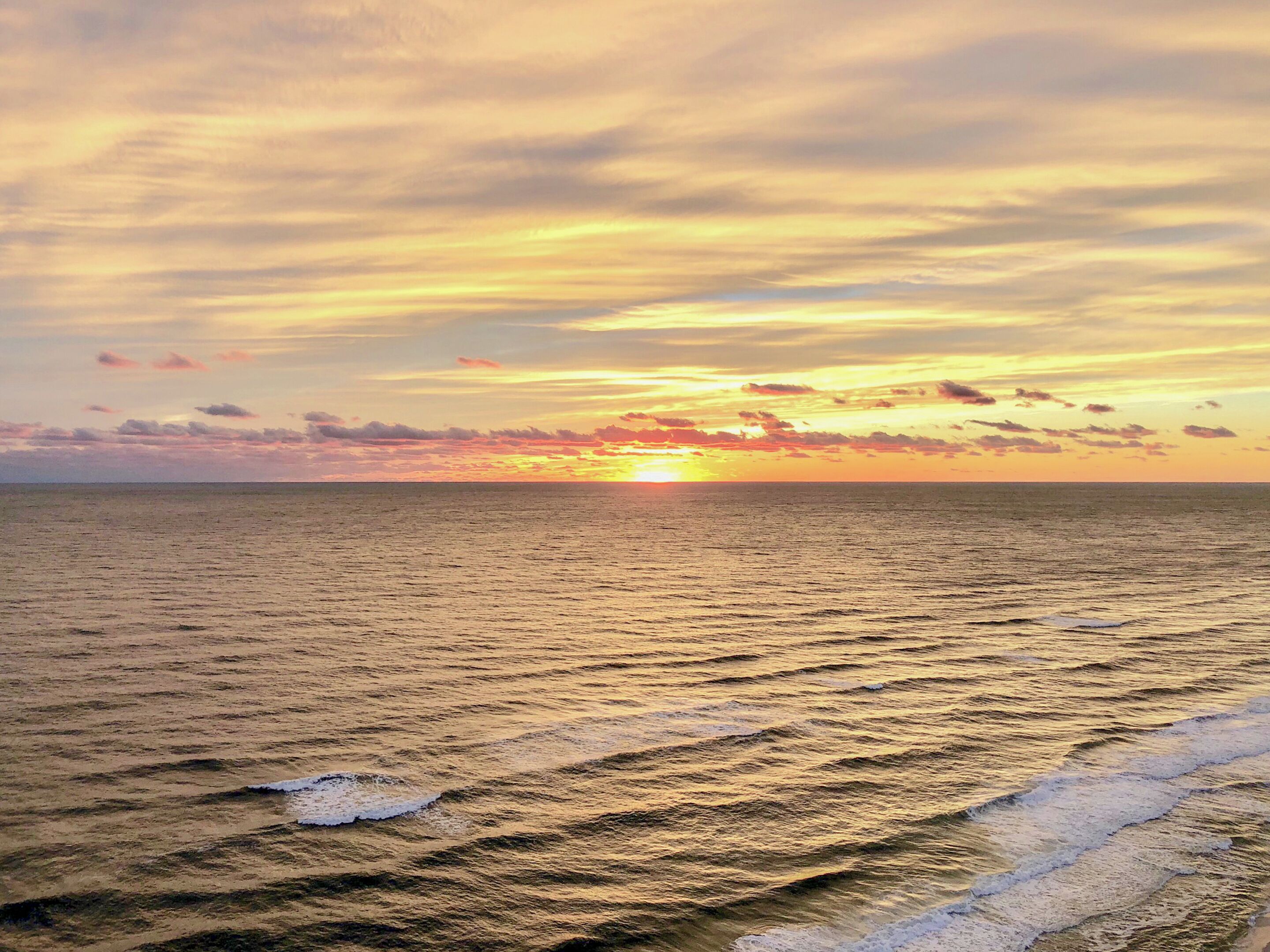 Een strand met golven en een zonsondergang.