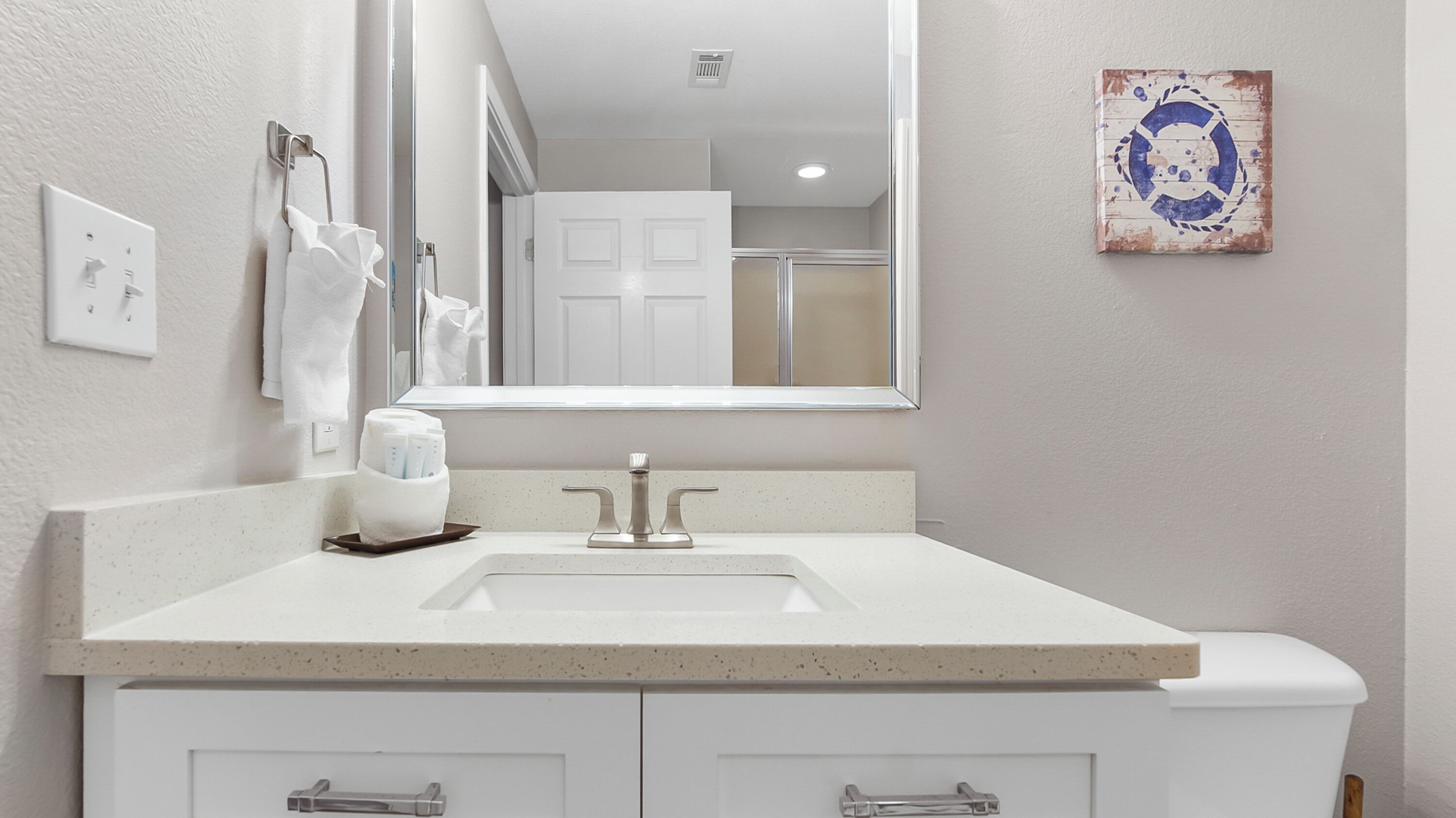 Un bagno con un lavandino bianco, uno specchio e un porta asciugamani.
