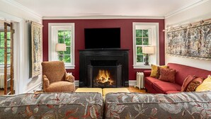 A living room with a fireplace, two patterned sofas, a red couch, and a large painting on the wall. - Castle Farms Wedding Weekend Home (Charlevoix)