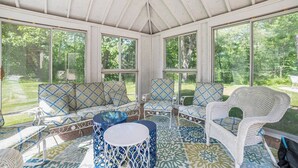 A covered patio with a sofa set, chairs, and a round table. - Castle Farms Wedding Weekend Home (Charlevoix)