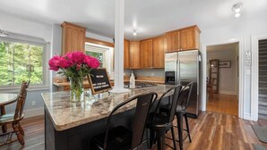 A modern kitchen with wooden cabinets, a stainless steel refrigerator, a marble countertop, and a sign indicating Wi-Fi and a password. - Castle Farms Wedding Weekend Home (Charlevoix)