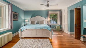 A bedroom with a bed, a ceiling fan, a window, and a radiator. - Castle Farms Wedding Weekend Home (Charlevoix)