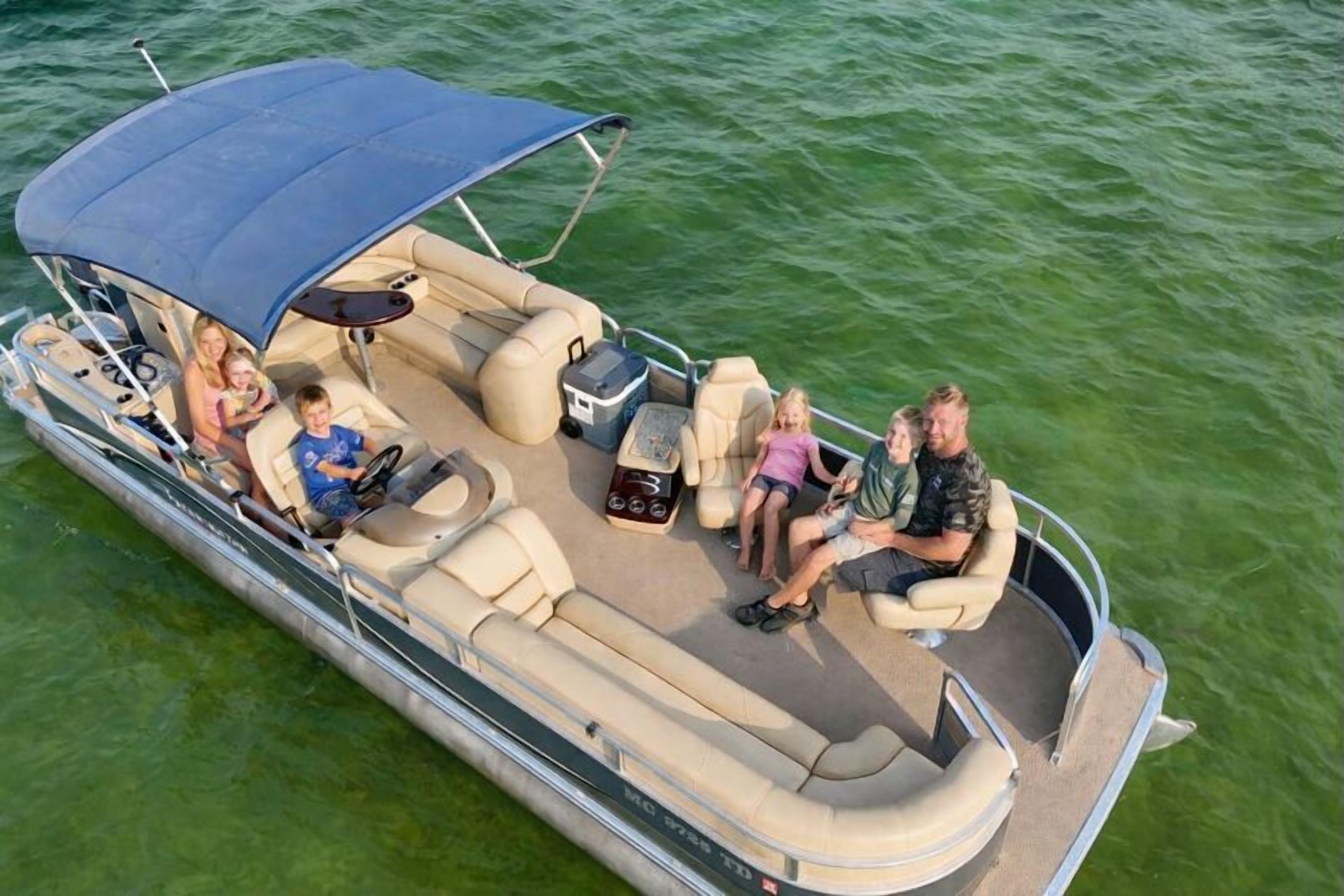 A boat with a covered seating area, a table, and a cooler.