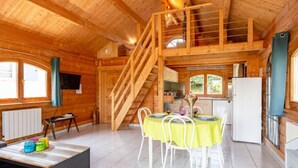 A wooden cabin interior with a dining area, kitchen, and a loft bedroom. - Le Chamalo by Interhome (Saint Georges de la Rivière)