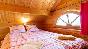 A cozy wooden cabin bedroom with a bed, pillows, and a window. - Le Chamalo by Interhome (Saint Georges de la Rivière)