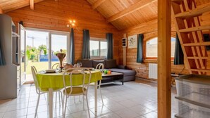 A cozy cabin interior with a dining area, a sofa, and a staircase. - Le Chamalo by Interhome (Saint Georges de la Rivière)