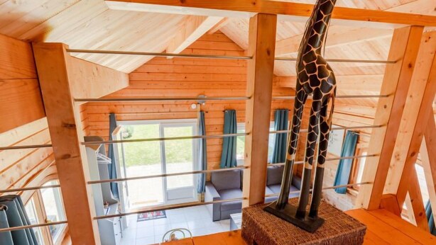 A wooden interior with a giraffe sculpture, wooden beams, and a view through a window. - Le Chamalo by Interhome (Saint Georges de la Rivière)