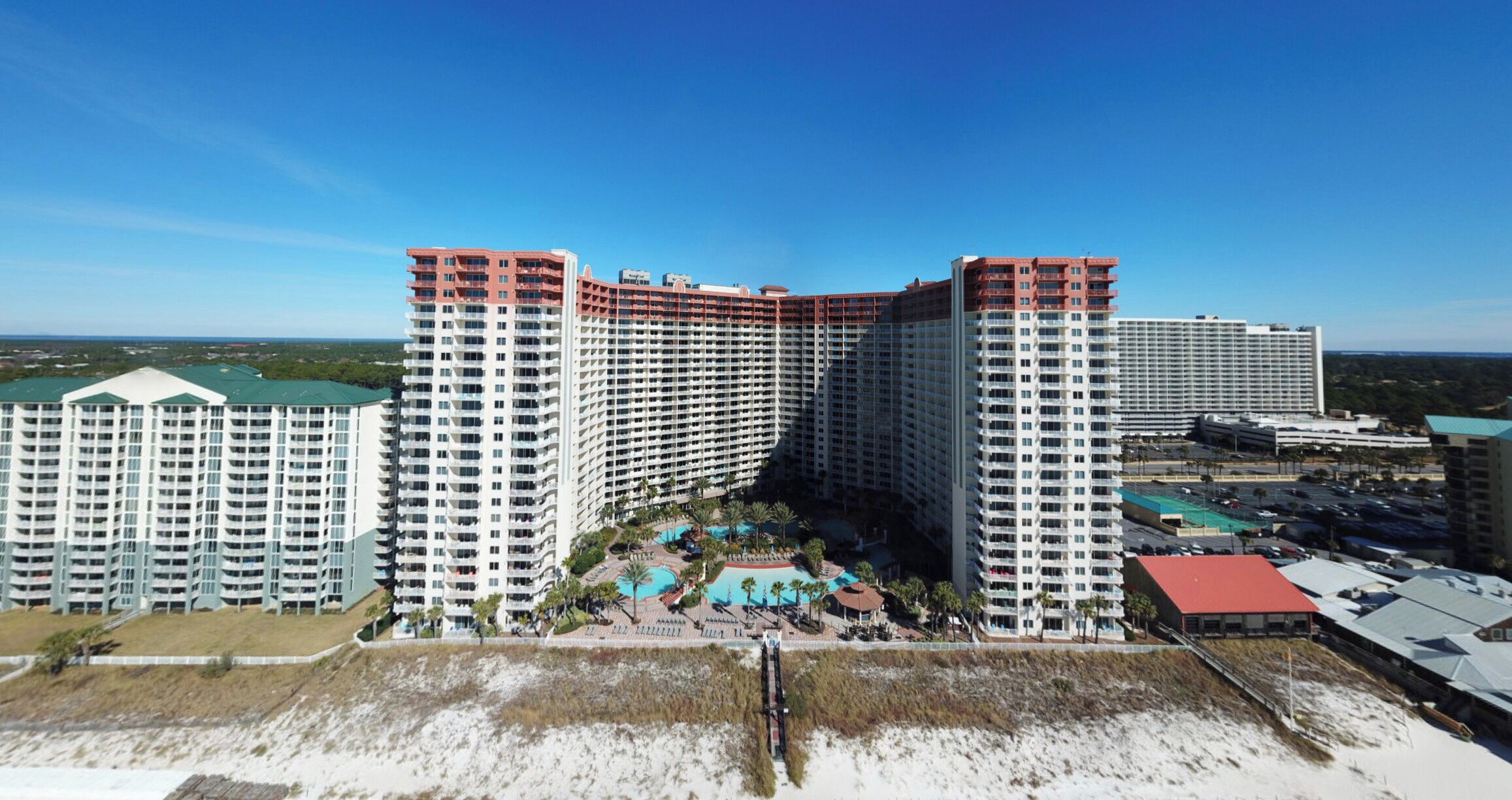 Un hôtel de grande hauteur, avec de nombreux étages, une piscine et une vue sur la plage.