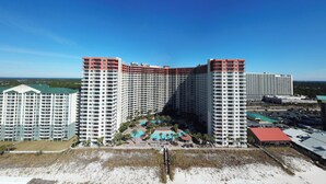 A high-rise hotel with multiple floors, a pool area, and a beach view.