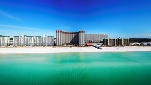 A beachfront hotel with multiple high-rise buildings, a pier extending into the water, and a sandy beach.