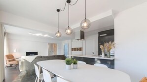 A modern kitchen with a large island, white chairs, and pendant lighting. - Miramar with terrace by Interhome (Oostende)