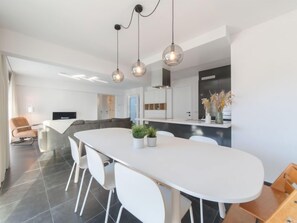 A modern kitchen with a large island, white chairs, and pendant lighting. - Miramar with terrace by Interhome (Oostende)