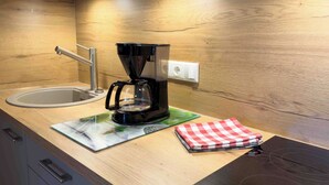 Una cucina con una macchina da caffè, un lavello e un piano di lavoro coperto da una tovaglia a quadri.