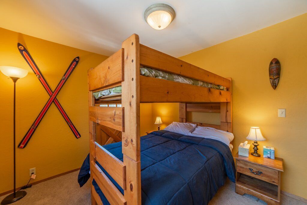 Habitación con literas, cabecera de madera, dos lámparas de noche y un esquífono en la pared.