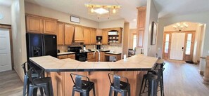 A spacious kitchen with a large island, wooden cabinets, and a modern chandelier.