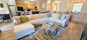 A modern living room with a sectional sofa, a coffee table, and a kitchen in the background.