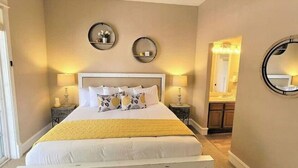 Un dormitorio ordenado con una cama grande, lámparas de noche y un espejo en la pared.