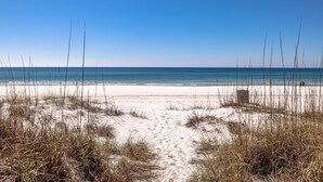 Une plage de sable fin, sous un ciel bleu clair et une mer calme.