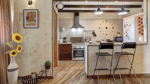 Una cocina con un reloj, taburetes de bar y techo de madera.