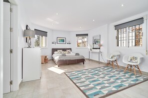 A bedroom with a bed, bedside tables, a desk, chairs, and a patterned rug. - Villa 'Casa Alba' with Sea and Mountain View, Pool, Garden & Wi-Fi (Salobreña)