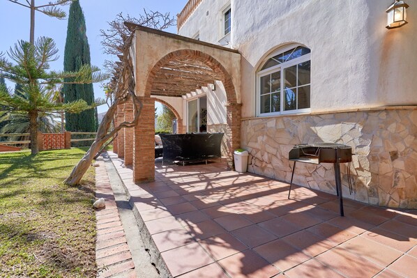 Un patio con una parrilla, una pérgola y un muro de piedra.