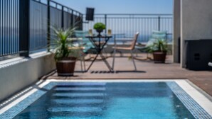 Una piscina con sillas de descanso y plantas en macetas.