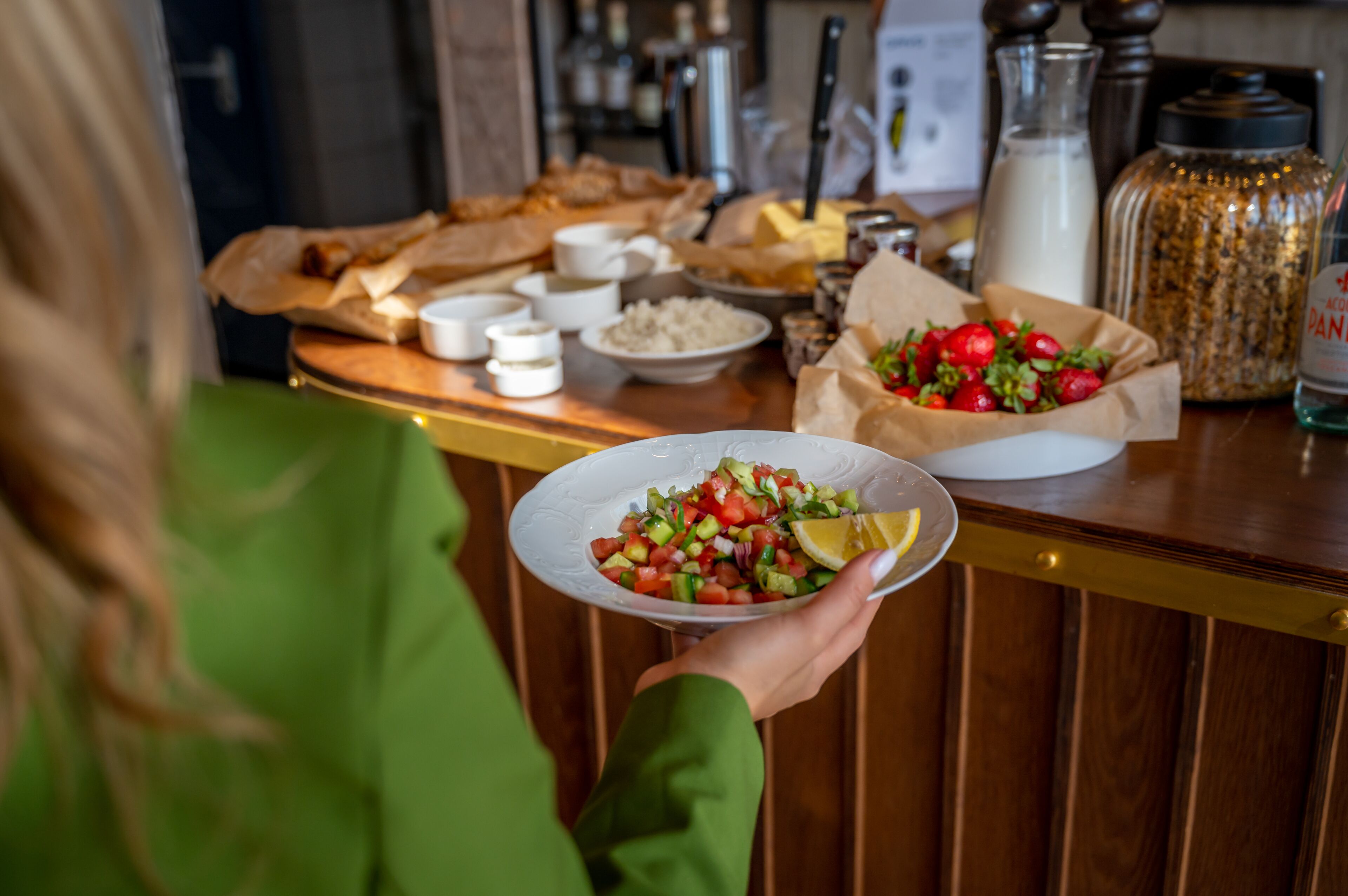 Una persona sosteniendo un plato de ensalada fresca con una rodaja de limón.