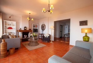 Un salon avec une cheminée, un coin repas et une cuisine à l’arrière-plan.