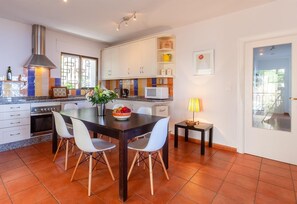 Una cocina moderna con comedor, armarios blancos, una estufa y un amplio ventanal.
