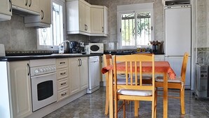 Eine Küche mit Esstisch, Stühlen, einer Mikrowelle, einem Herd und einem Kühlschrank.