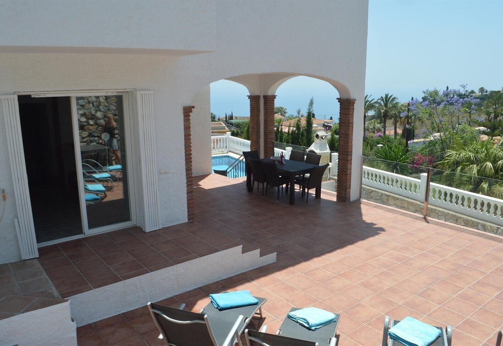 A covered patio with a pool, outdoor seating, and a view of the sea.