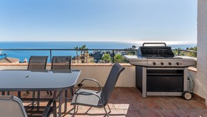 Une terrasse extérieure équipée d’un barbecue, de sièges et offrant une vue sur l’océan.