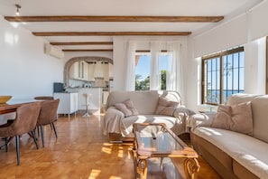 Ein Wohnzimmer mit einer Couch, einem Couchtisch und einem Essbereich mit Stühlen.