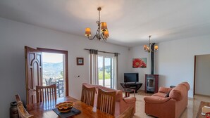 Uma área de refeições com mesa e cadeiras de madeira, televisão, sofá e lareira.