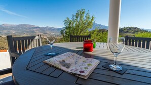 Uma mesa de madeira com dois copos de vinho, um menu e um pote vermelho.