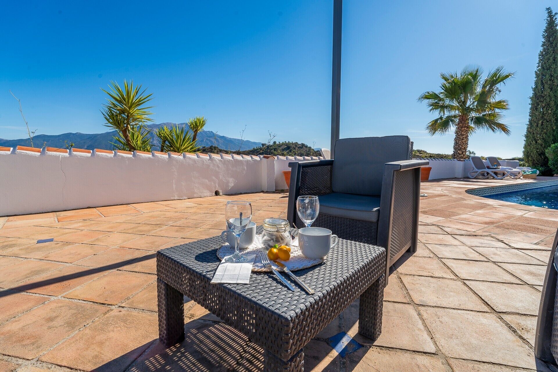 Une terrasse sur le toit avec une table dressée pour deux personnes, une piscine et une vue sur les montagnes.