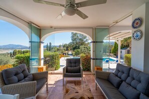 Un patio techado con vista a una piscina y montañas.