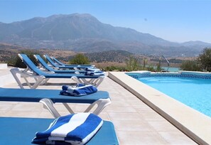Un espace aménagé au bord de la piscine, avec des chaises longues et une piscine, le tout entouré de montagnes.