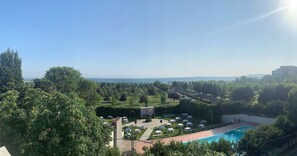A pool area with lounge chairs and umbrellas, surrounded by lush greenery and a clear sky. - Talen Otel (Istanbul)