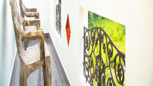 A balcony with a view of lush greenery, a metal railing, and a chair. - Rainbow Residency ECR (Vanur)