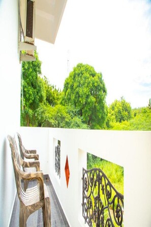 A balcony with a view of lush greenery, a metal railing, and a chair. - Rainbow Residency ECR (Vanur)