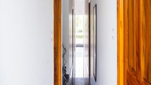 A hallway with wooden doors, a blue carpet, and framed pictures on the walls. - Rainbow Residency ECR (Vanur)