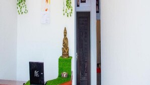 A reception desk with a laptop, a statue, and hanging plants. - Rainbow Residency ECR (Vanur)