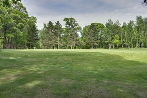 Un campo de golf con un fairway bien cuidado, un putting green y una densa línea de árboles al fondo.