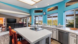 Une cuisine moderne dotée d’un îlot central, de grandes fenêtres et offrant une vue sur l’extérieur.