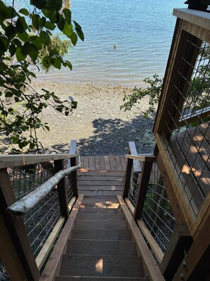Eine Holztreppe führt zu einem Strand mit Blick auf das Wasser.